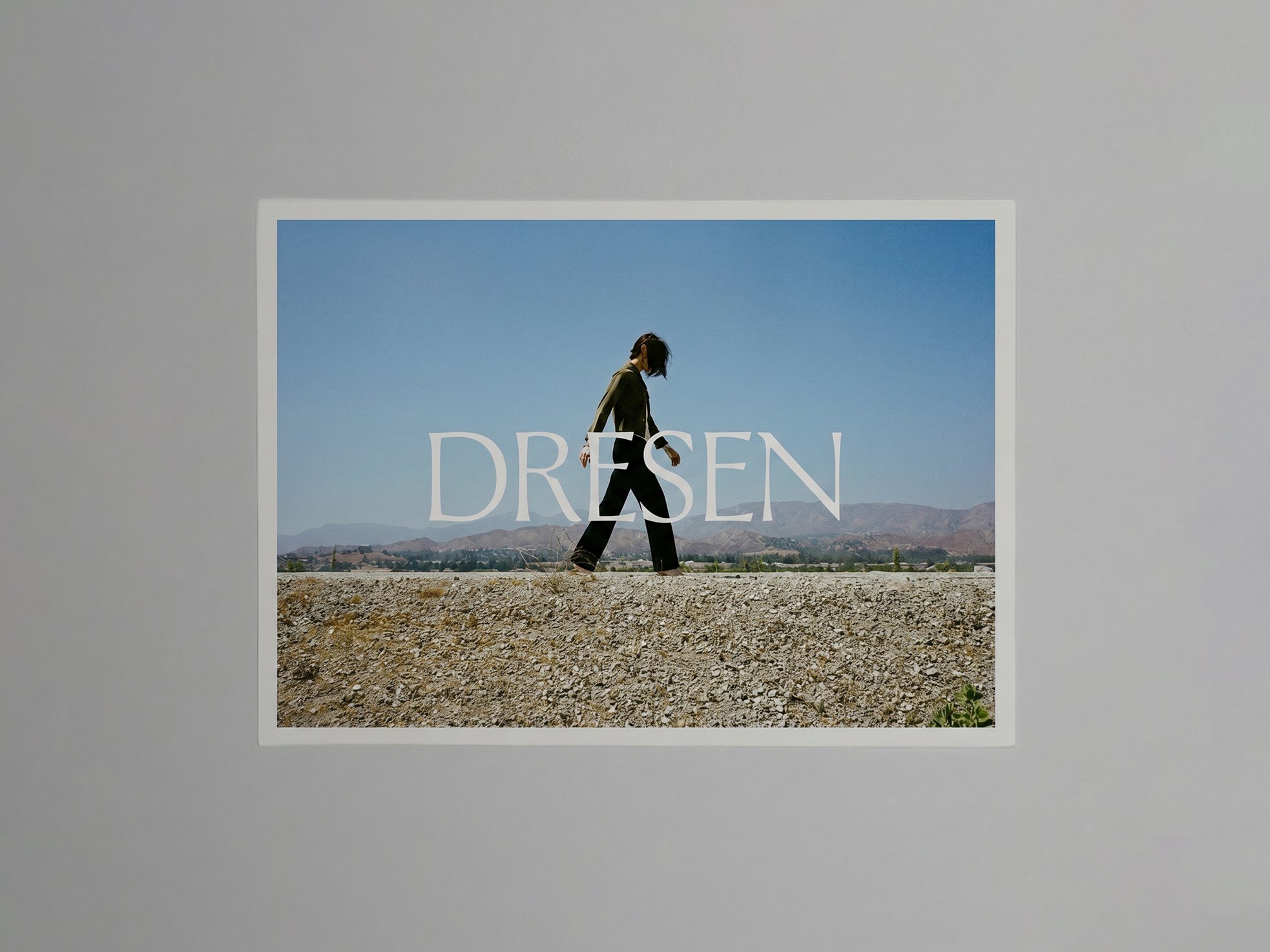 Dresen identity: printed poster with the Dresen logotype over a figure walking in a desert landscape